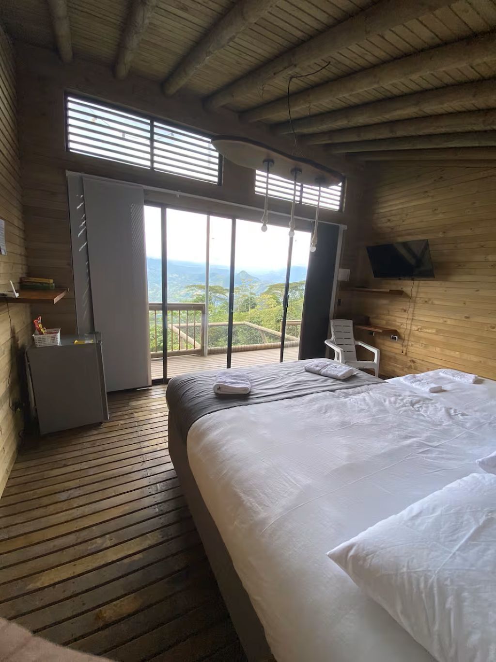 Een slaapkamer met een groot bed, een bureau, een stoel en een televisie aan de muur.