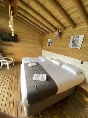 A wooden room with a bed, a TV, and artwork on the walls. - Exclusive Cabin + Private Panoramic Swimming Pool in Nocaima, Colombia (Nocaima)