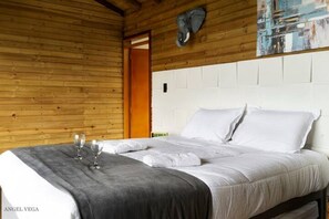 A wooden-paneled room with a bed, two wine glasses, and a towel on the bed. - Exclusive Cabin + Private Panoramic Swimming Pool in Nocaima, Colombia (Nocaima)