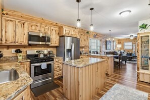 A kitchen with wooden cabinets, stainless steel appliances, and a central island. - Timber Tides-Lake Front/HotTub/6 Min to GOTL Strip (Ashtabula)