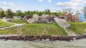 A residential area with houses along a riverbank, a grassy embankment, and a stone retaining wall.