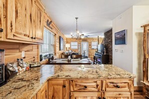 A kitchen with wooden cabinets, granite countertops, and a central island. - Timber Tides-Lake Front/HotTub/6 Min to GOTL Strip (Ashtabula)