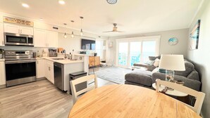 A modern kitchen with a dining area, a living room with a view, and a balcony.
