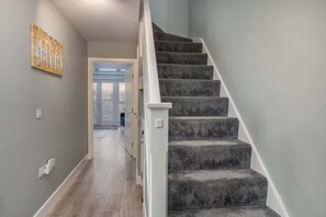 Eine Treppe mit Teppichbelag und weißen Geländern, die zu einer Tür führt.