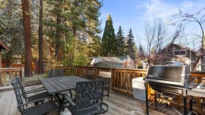 A wooden deck with a grill, dining table, and chairs. - Evergreen (Big Bear Lake)