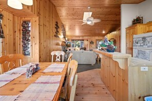 A wooden cabin interior with a dining area, a kitchen, and a living space. - Evergreen (Big Bear Lake)