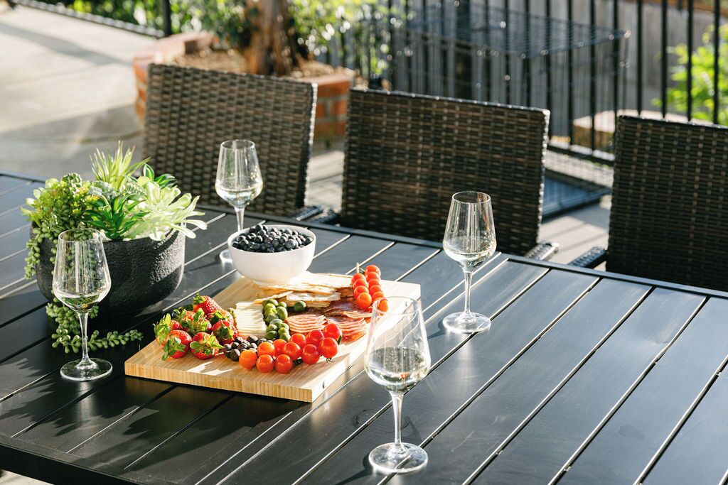 A table with a charcuterie board, a bowl of olives, and wine glasses.