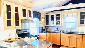 A kitchen with wooden cabinets, a stove, and a sink. - Spacious 2-Bedroom Coastal Retreat with Luxurious Marble Shower – Beaufort, NC (Beaufort)