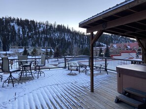A snow-covered deck with outdoor seating and a view of a snowy landscape and buildings. - Alpine Summit Lodge - Formally 4K Penthouse View (Red River)