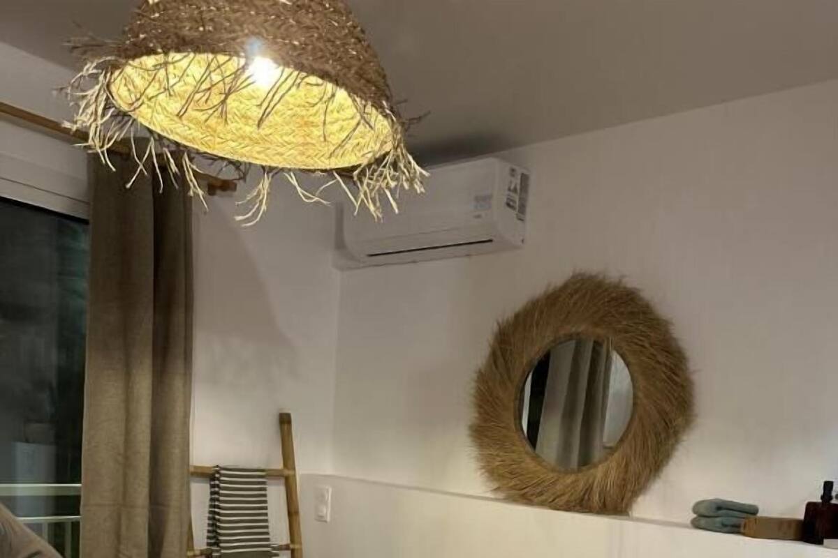 Un lit avec une couvre-lit à motifs, deux oreillers et une lampe suspendue.