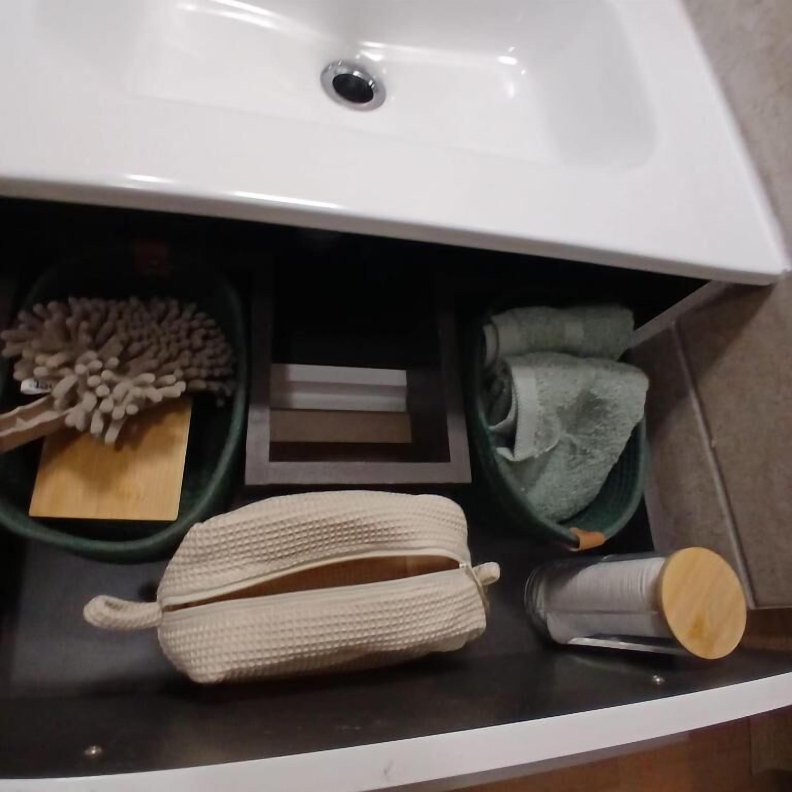 Ein Badezimmer mit einem weißen Waschbecken, einem Holzschneidebrett, einer grünen Schüssel mit weißen Bohnen, einem beigen Handtuch und einem kleinen Holzkästchen.