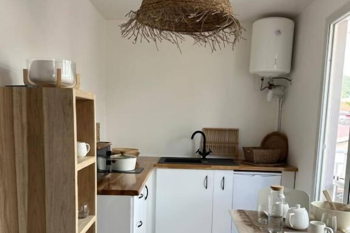 Une cuisine moderne avec des armoires blanches, une table en bois et un luminaire suspendu.