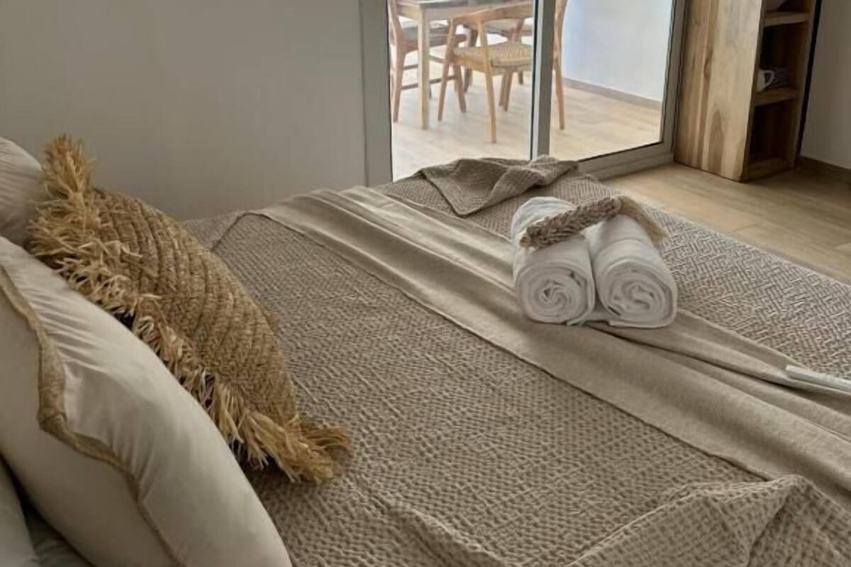 Une chambre avec un lit, une grande fenêtre et une vue sur un espace de restauration extérieur.