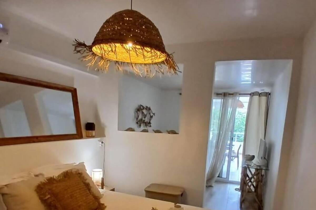 Une chambre avec un lit, un luminaire suspendu, un miroir et une vue sur le balcon.