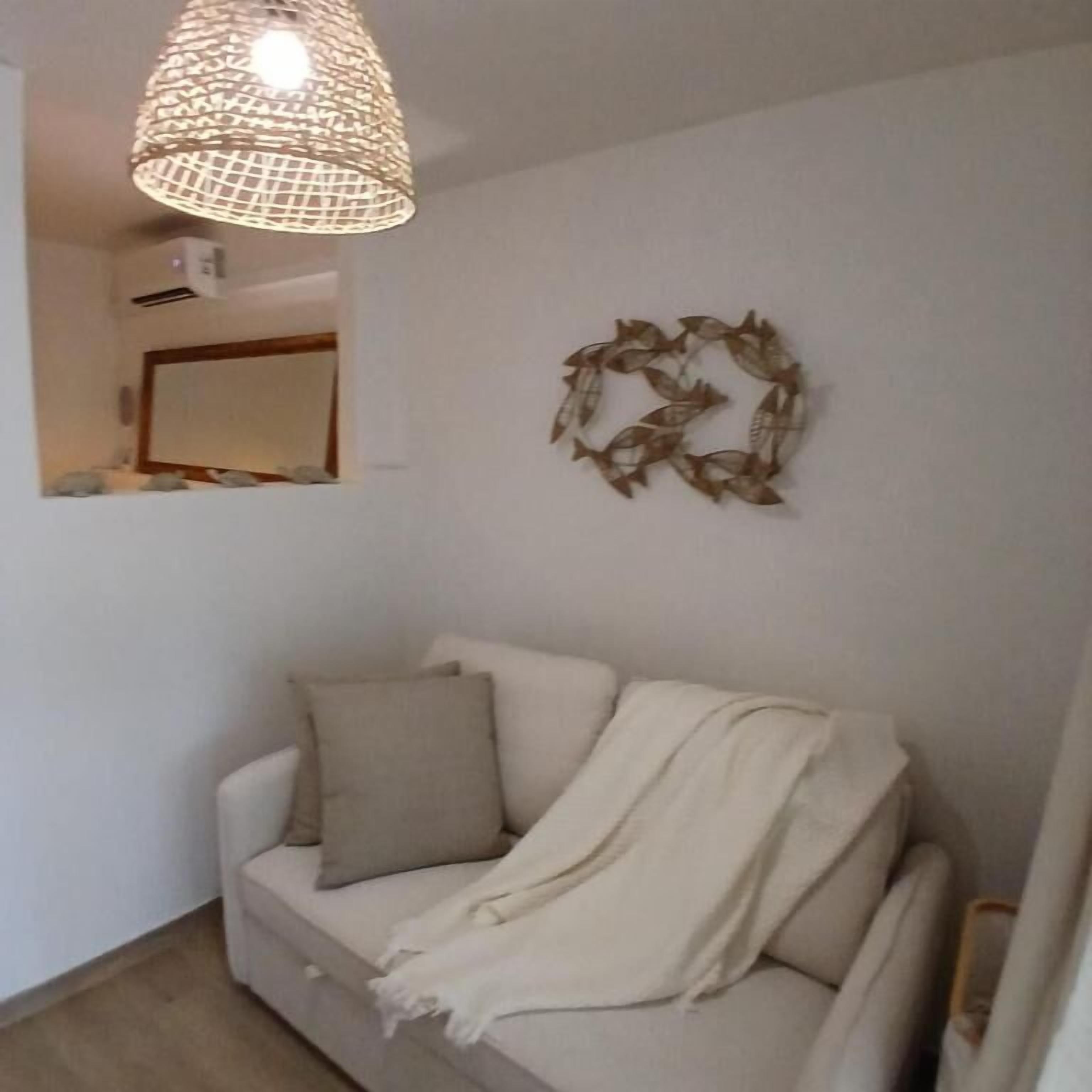 A living room with a sofa, a hanging light fixture, and a wall decoration.