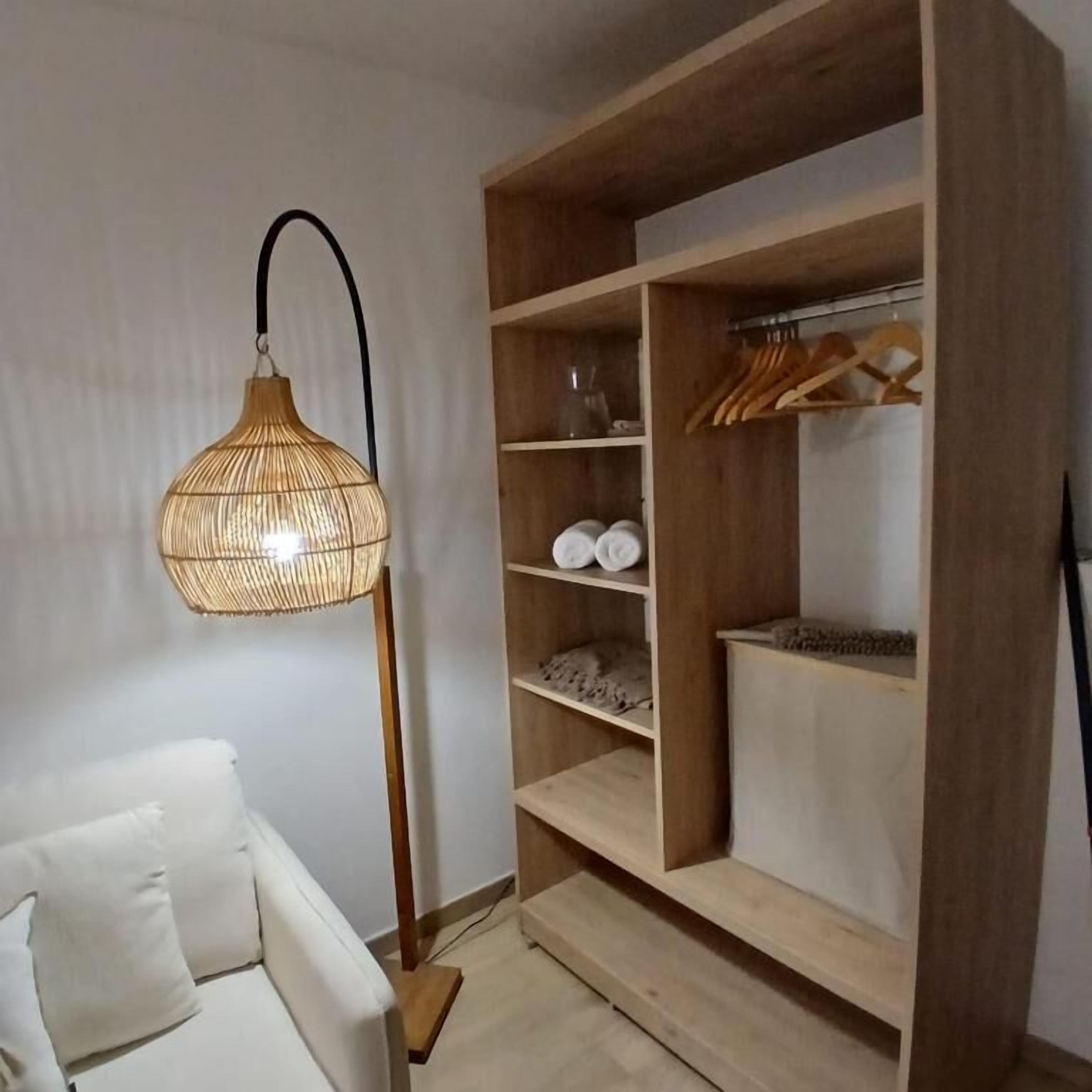 Habitació amb un sofà blanc, un armari de fusta amb prestatges i una làmpada d'espart.