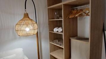 Habitació amb un sofà blanc, un armari de fusta amb prestatges i una làmpada d'espart.