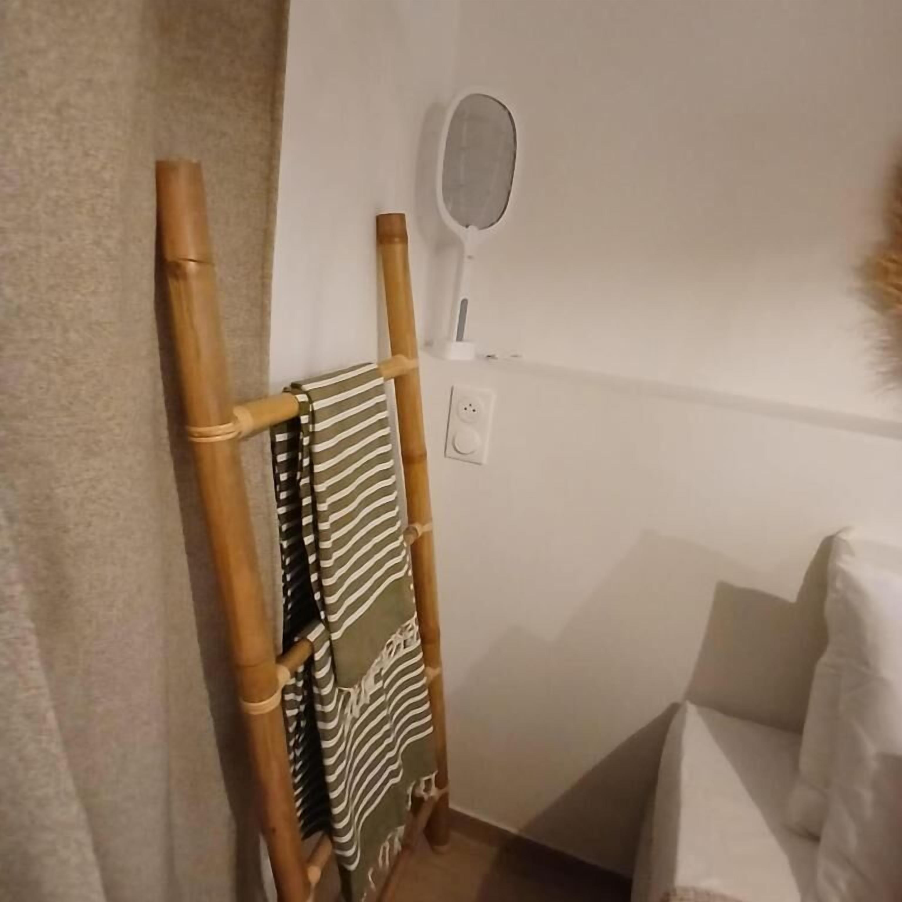 Huoneessa on puinen pyyheteline, raidallinen pyyhe, seinälle kiinnitetty peili ja valkoinen sohva.