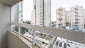 Un immeuble de grande hauteur, doté de nombreux étages et de balcons, offrant une vue sur l’agglomération environnante et s’ouvrant sur un ciel dégagé.