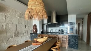 A modern kitchen with a central island, stone wall, and a hanging light fixture. - Department La Cruz de Huanacaxtle, Nayarit. With two bedrooms with bathroom (Cruz de Huanacaxtle)