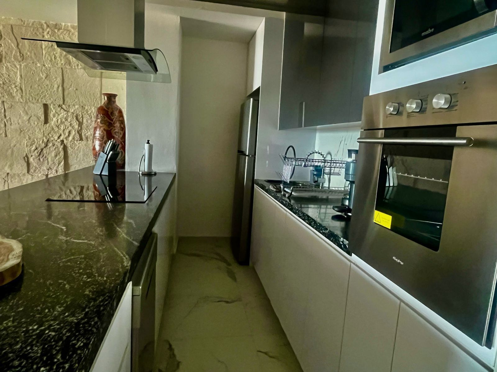 Een moderne keuken met roestvrijstalen apparatuur, een marmeren aanrechtblad en een achterwand van natuursteen.