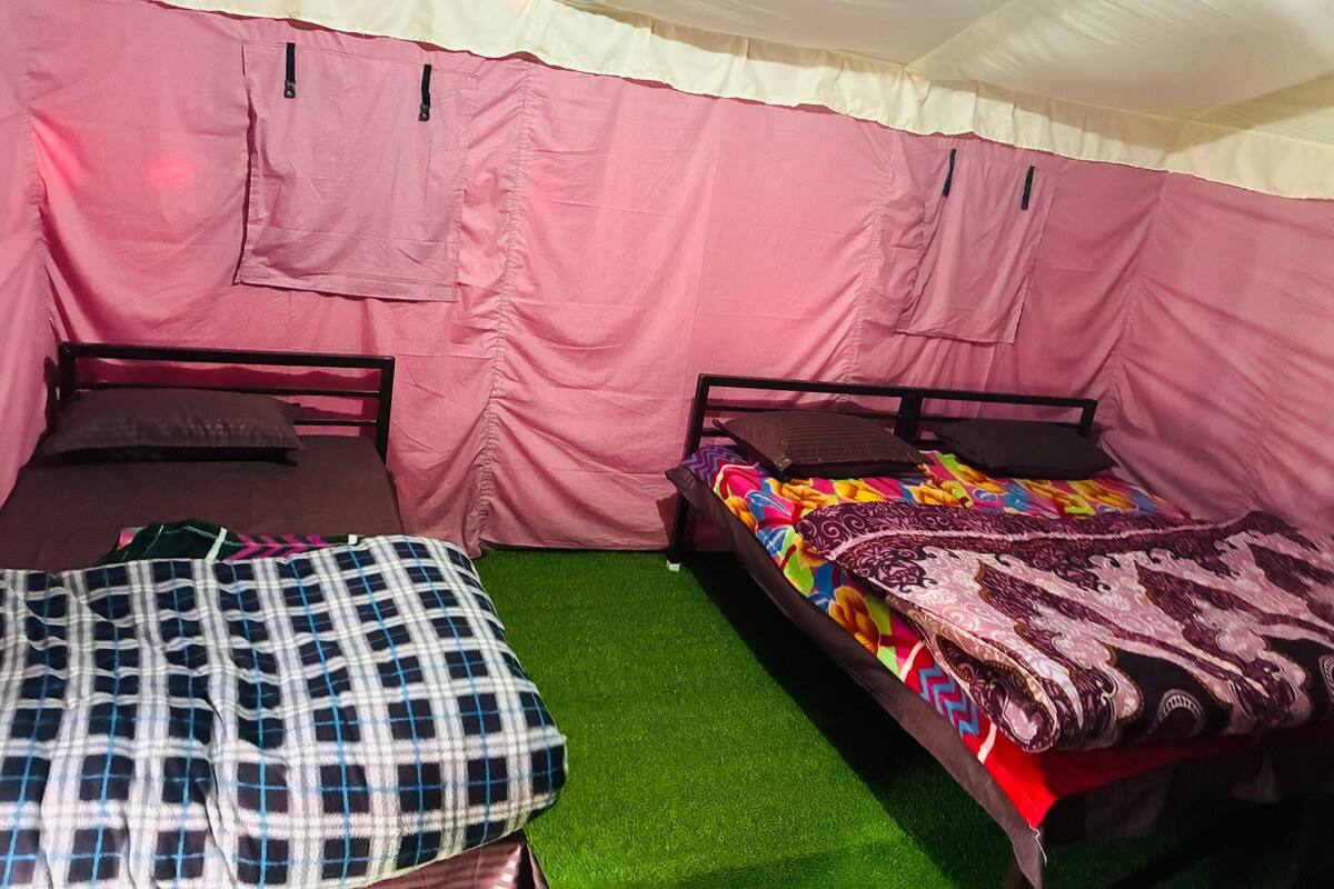 Una carpa con dos camas, cada una con una almohada y una manta.