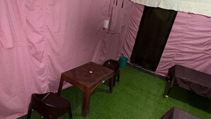 Una tenda con tavolo e sedie, prato artificiale verde e una porta nera.