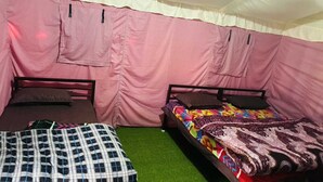 Una tenda con due letti, ognuno con un cuscino e una coperta.