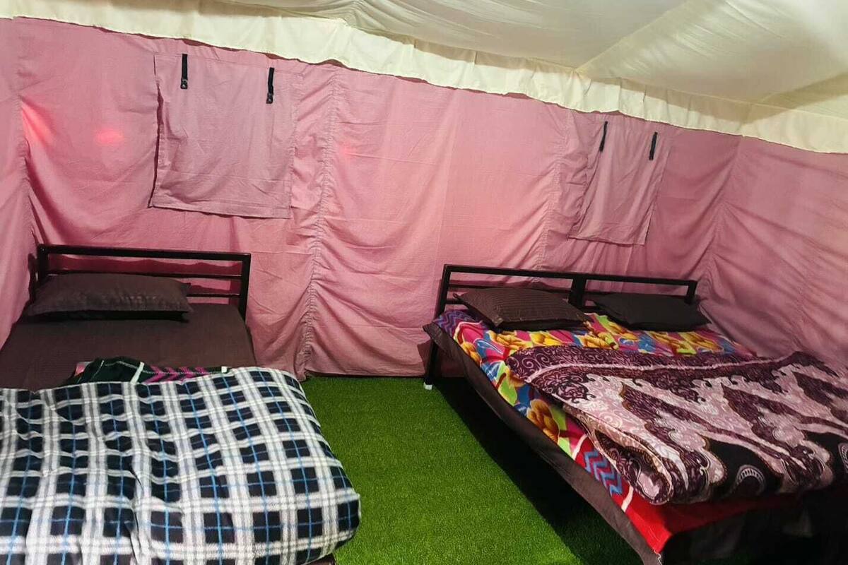 Una carpa con dos camas, cada una con almohada y manta.