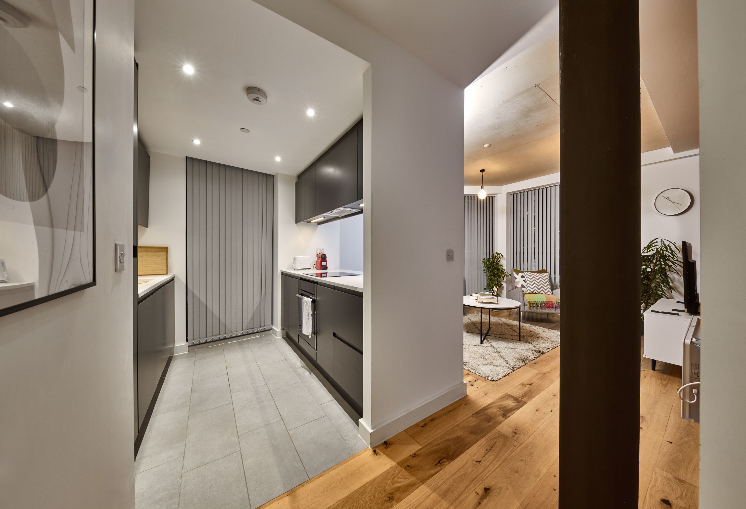 A modern kitchen with dark cabinets, a white countertop, and a wooden floor.
