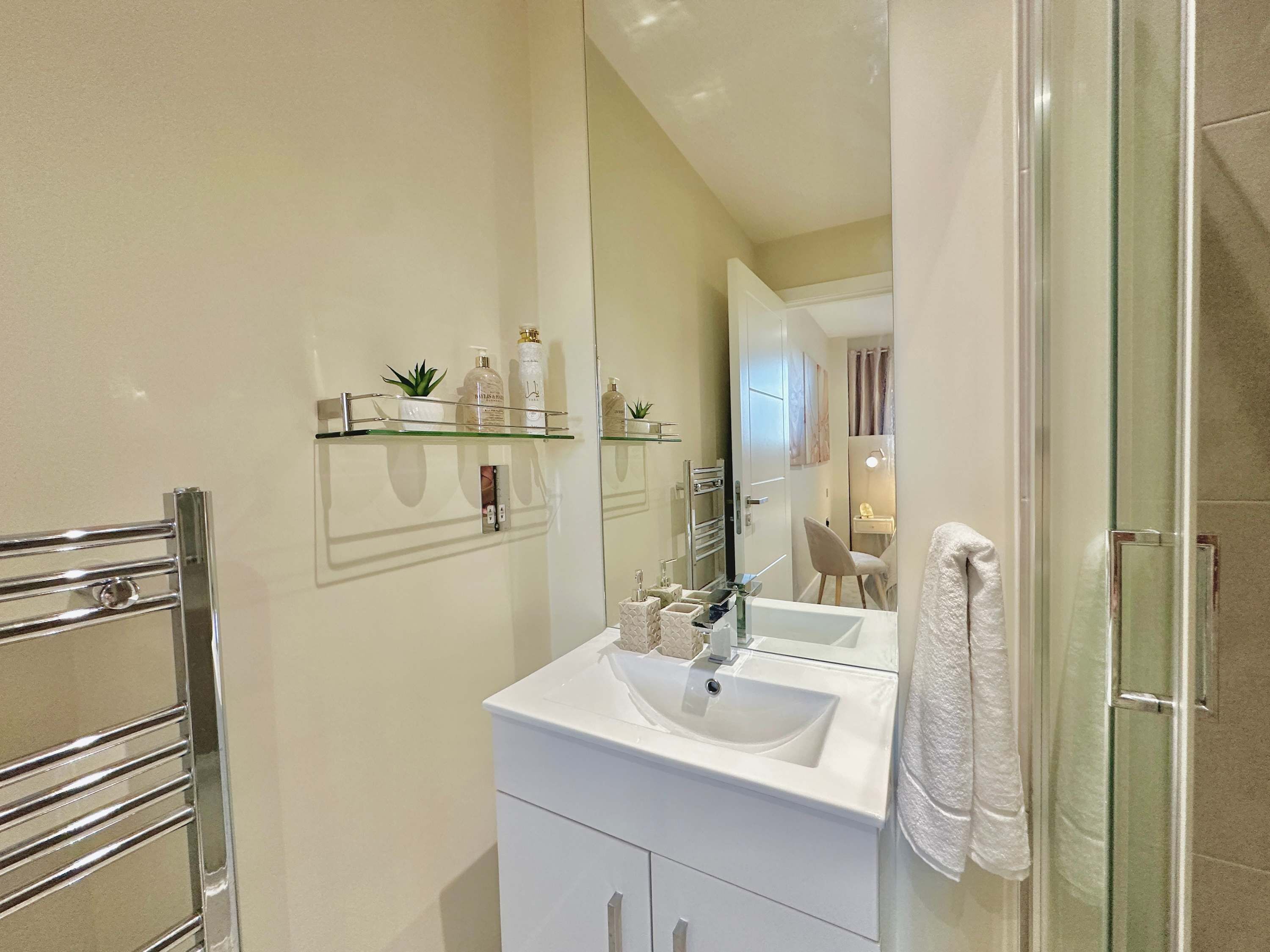 A bathroom with a glass shower enclosure, a white sink, and a mirror above it.