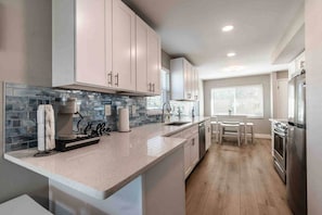 A modern kitchen with a central island, a built-in oven, and a dining area with a table and chairs. - Waterfront Modern and Spacious Condo 2 Bed/2bath (Clearwater)