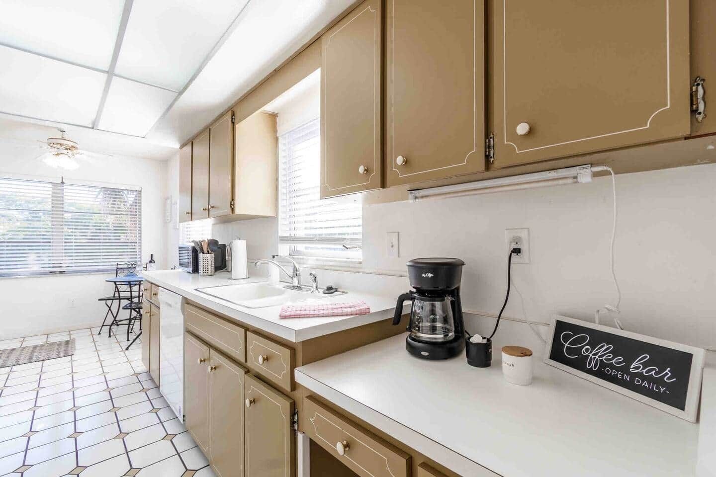 Een keuken met beige kastjes, een koffiezetapparaat en een bord dat een koffiebar aangeeft.