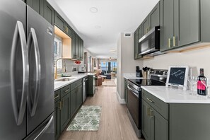A modern kitchen with stainless steel appliances, dark cabinetry, and a central island. - Beautiful waterfront 2 bedroom condo (Clearwater)