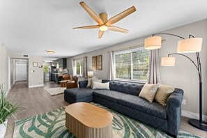 A modern living room with a sectional sofa, a wooden coffee table, and a ceiling fan. - Beautiful waterfront 2 bedroom condo (Clearwater)