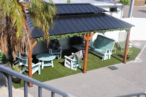 A covered outdoor seating area with a table and chairs, a grill, and a bench. - Waterfront Condo in Dunedin/Clearwater (Clearwater)