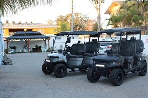 A golf cart with seating, parked in a covered outdoor area with tables and chairs. - Waterfront Condo in Dunedin/Clearwater (Clearwater)