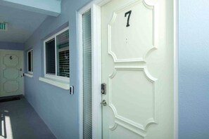 A hallway with doors numbered 6 and 7, a window with blinds, and a door with a textured glass panel. - Waterfront Condo in Dunedin/Clearwater (Clearwater)