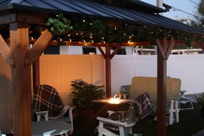 A covered patio area with a fire feature, seating, and a small plant. - Serene Shore Retreat (Clearwater)