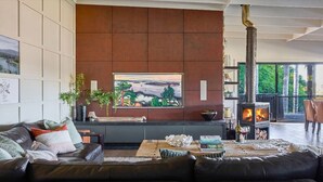 A living room with a fireplace, a sofa, a coffee table, and a painting on the wall. - Grants - spacious riverside escape on the Shoalhaven River (Longreach)