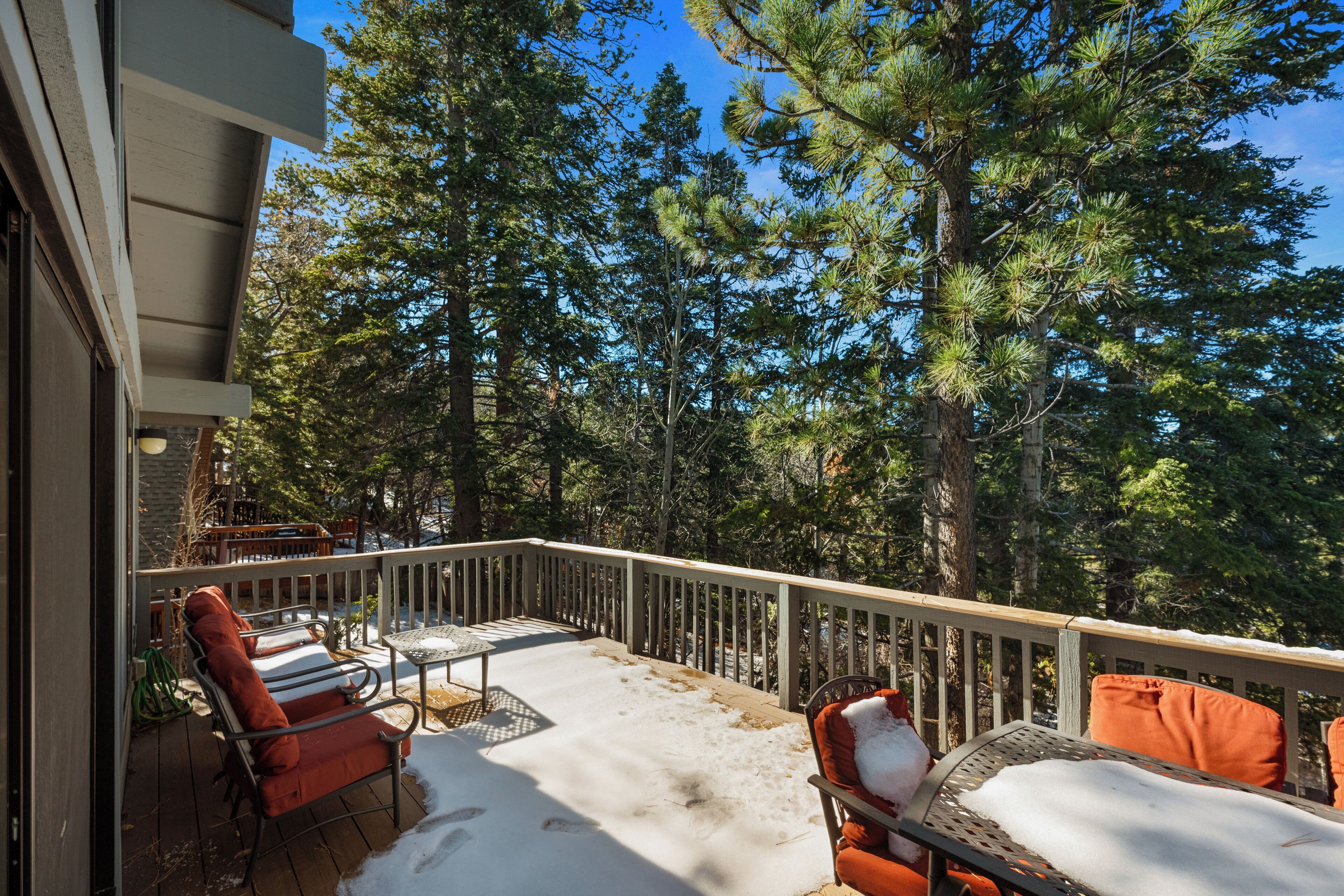 Une terrasse dotée de mobilier d’extérieur, entourée d’arbres.