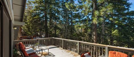 Une terrasse dotée de mobilier d’extérieur, entourée d’arbres.