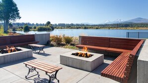 An outdoor patio with seating, fire pits, and a view of a lake and mountains.