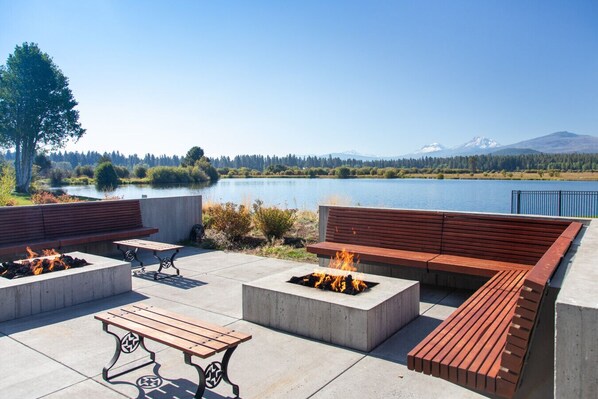 An outdoor patio with seating, fire pits, and a view of a lake and mountains.