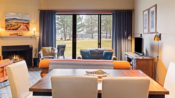 A cozy living room with a fireplace, a dining table, and a view of the outdoors.