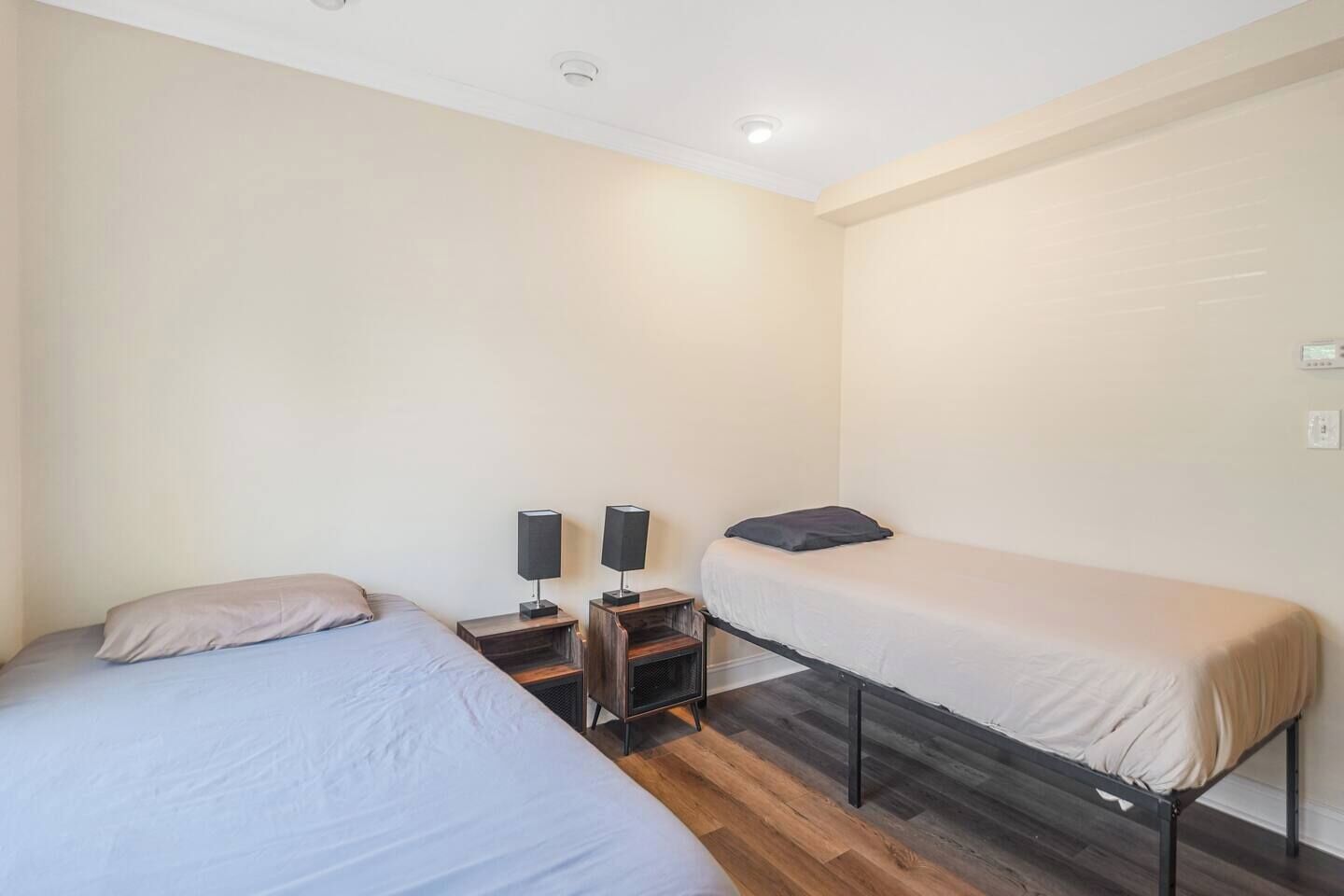 A room with two beds, a small table with speakers, and a wooden floor.