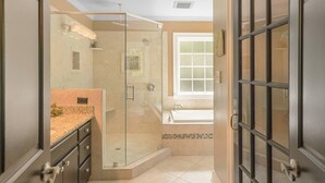 Une salle de bain avec une douche à parois de verre, un lavabo et une fenêtre.