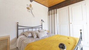 A bed with a metal frame, a yellow blanket, and a wall-mounted lamp. - Chalet Cottage 50 m from Lake with View, Private Terrace, and Wi-Fi (Le Vernet-Chaméane)