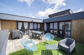 Eine Terrasse mit Tisch, Stühlen und Grill.