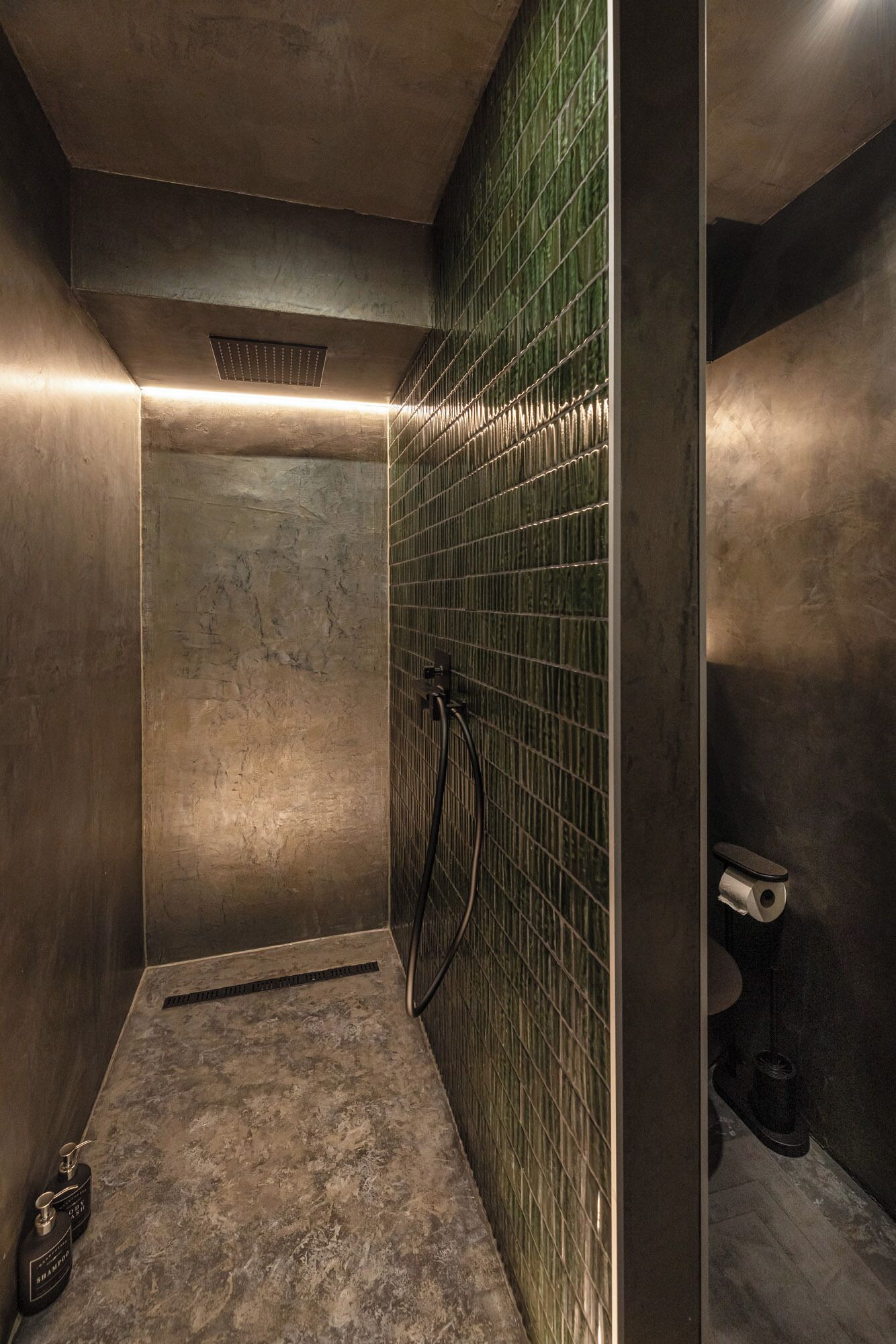 Een badkamer met een douche, betegelde wanden en een toilet.